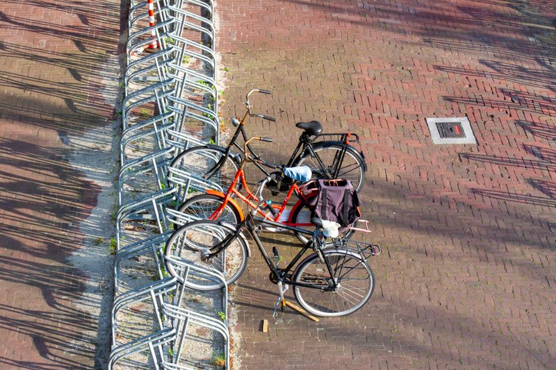 Overhead view of bicycles parked in a city bike stand with shadows on the pavement.