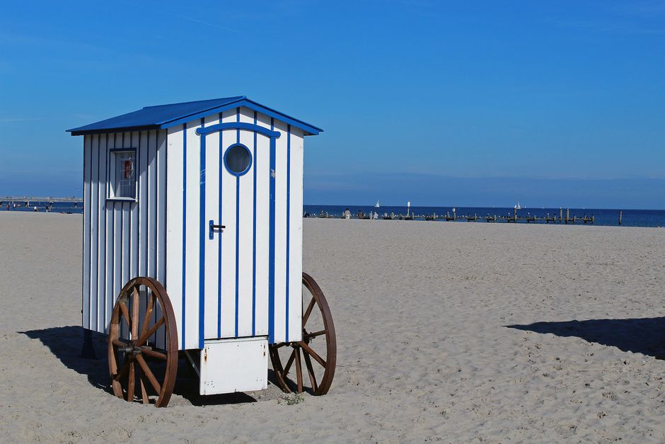 A traditional beach trolley on a sunny, sandy shore with blue skies and ocean view.