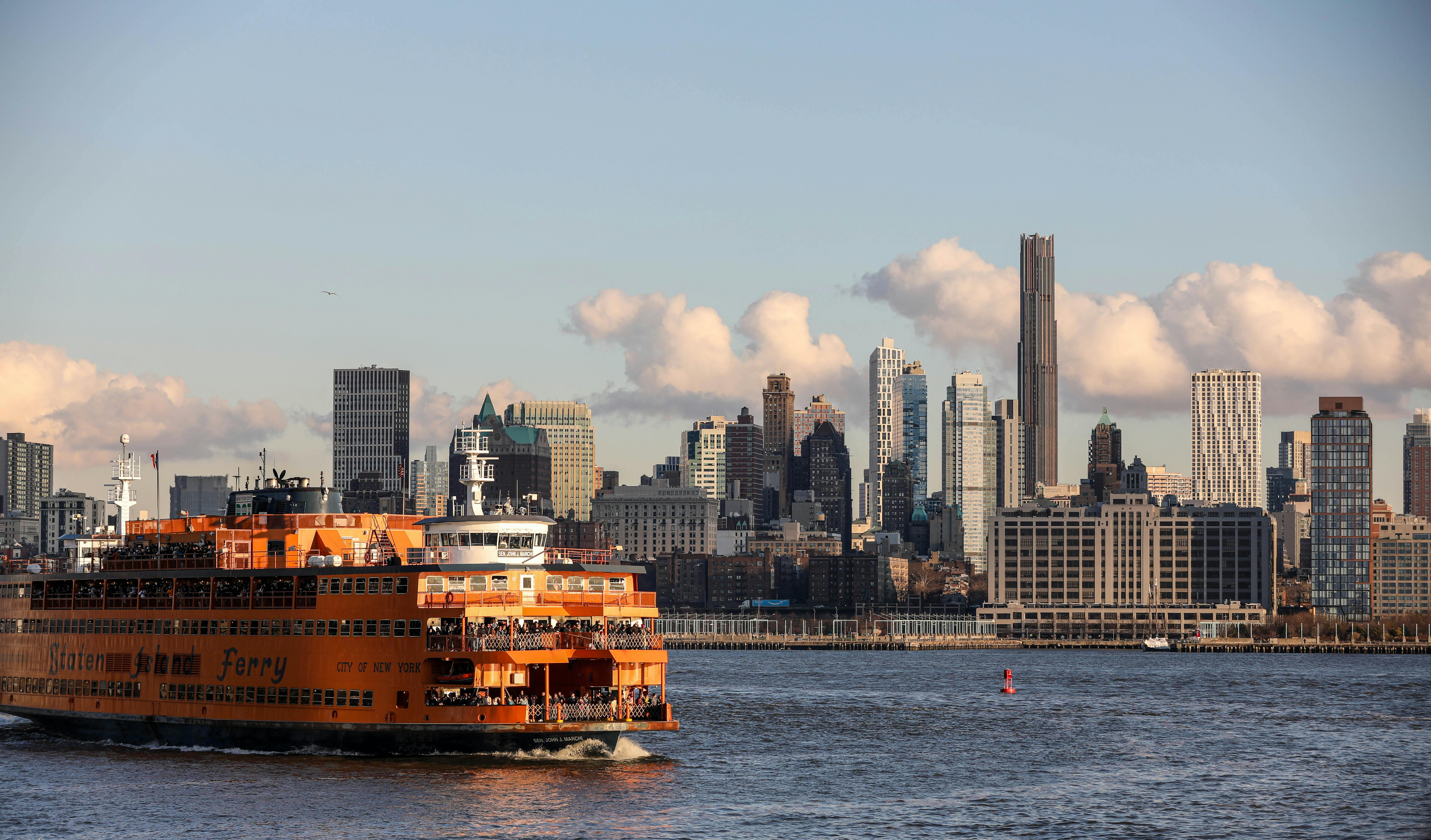 Staten Island Ferry crossing with New York City skyline in the background, vibrant and scenic day view