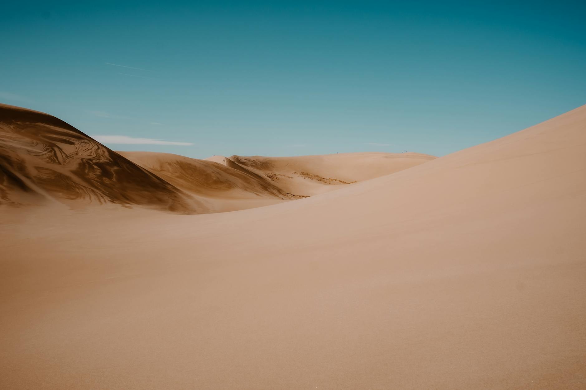Captivating view of expansive sand dunes in Colorado, showcasing serene natural beauty under a vibrant blue sky.
