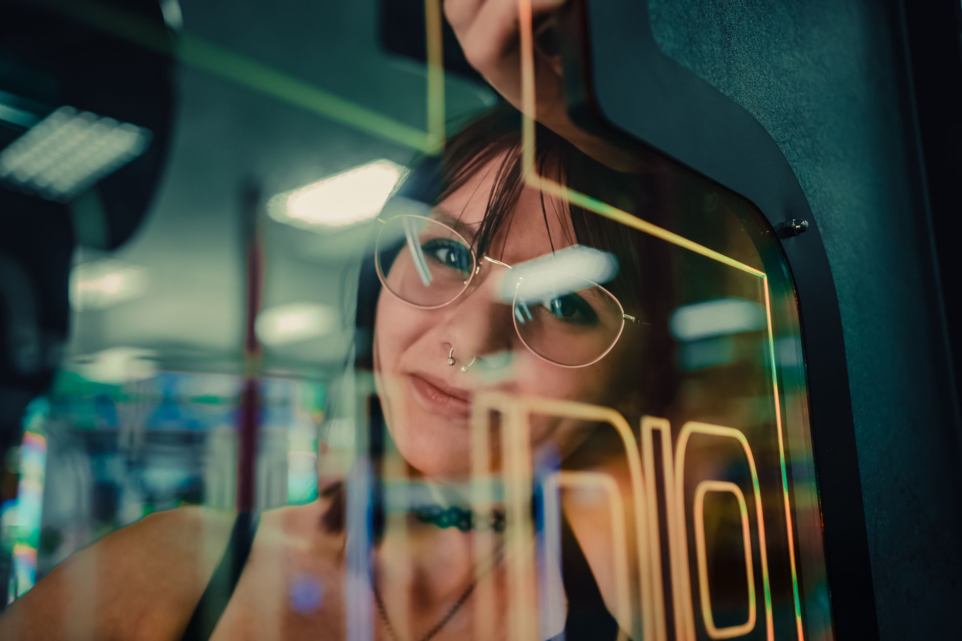 A woman reflected in arcade machine glass, enveloped in neon lights.