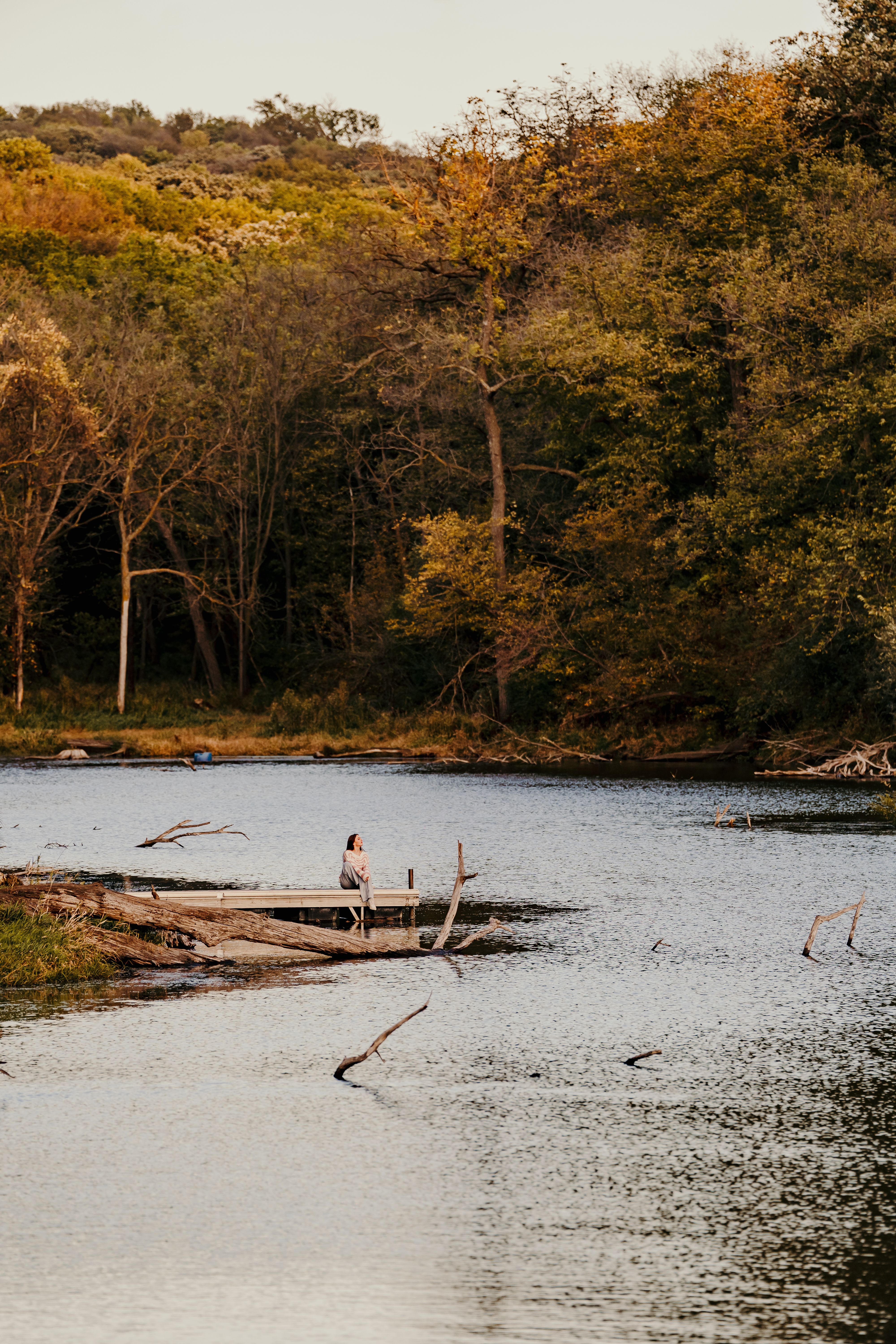 A person enjoying a peaceful moment by a scenic lakeside surrounded by autumn trees.