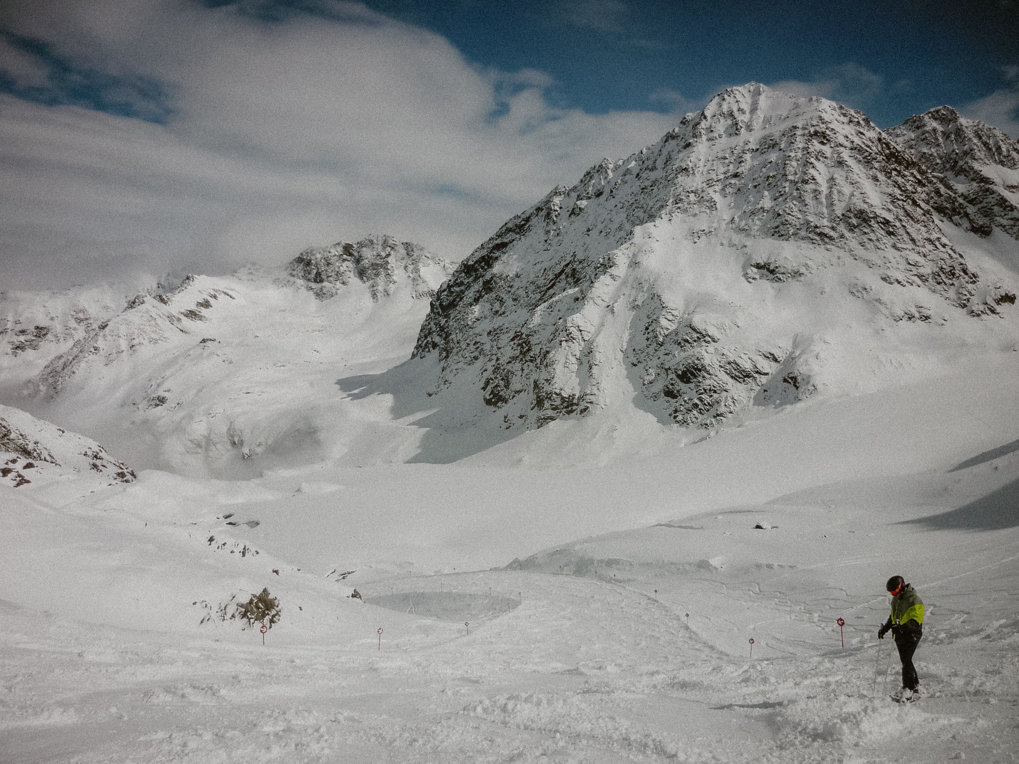 A skier enjoys a serene adventure in expansive snowy mountains under a clear sky.
