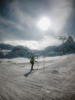 Skier enjoying a sunny day on snowy mountain slopes with ski lift.