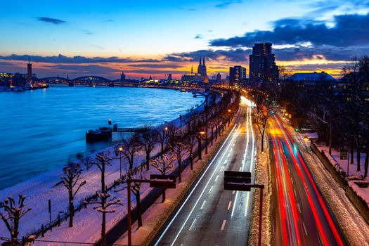 Vibrant evening view of Cologne with light trails and the iconic Cologne Cathedral at sunset.