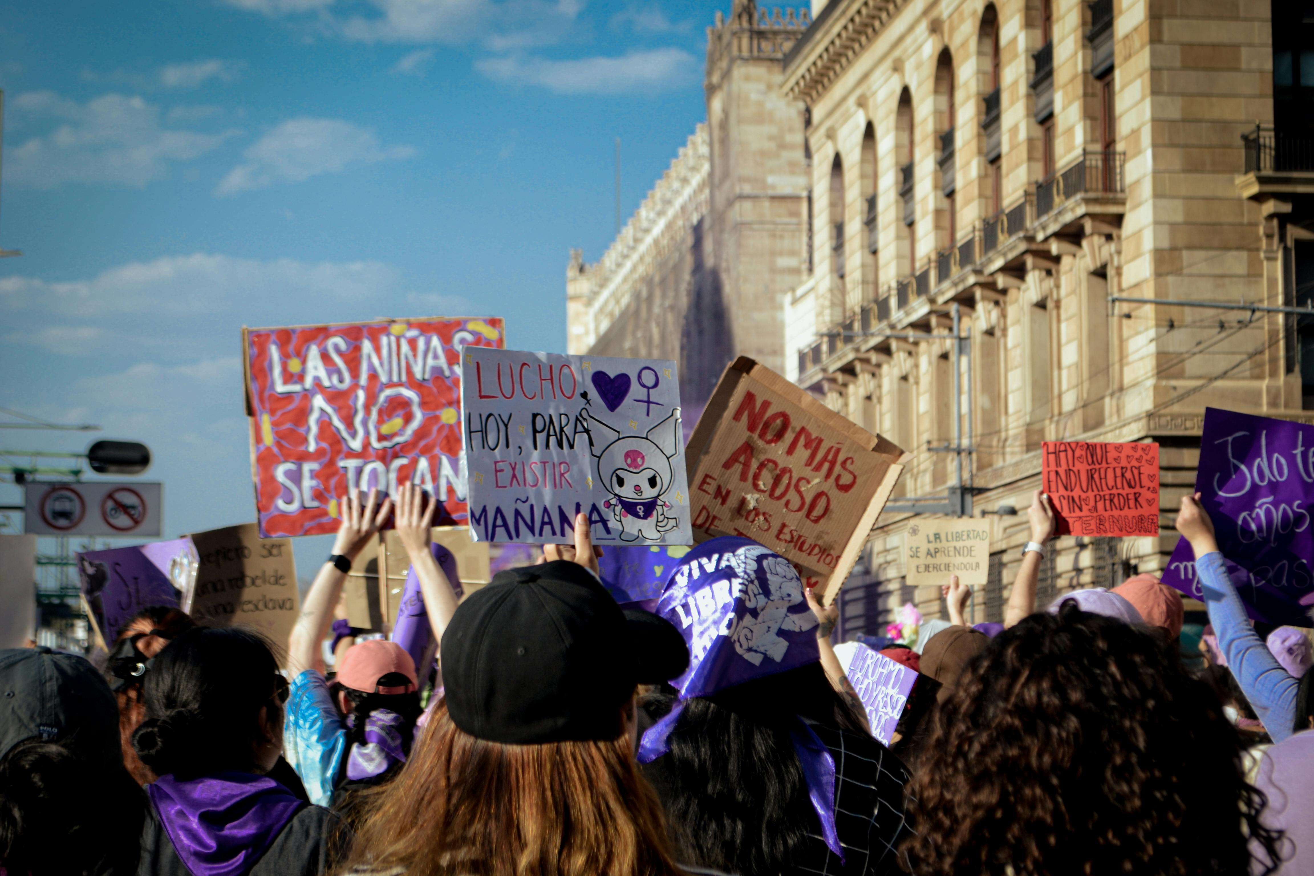 A vibrant outdoor women's rights demonstration with participants holding protest signs.