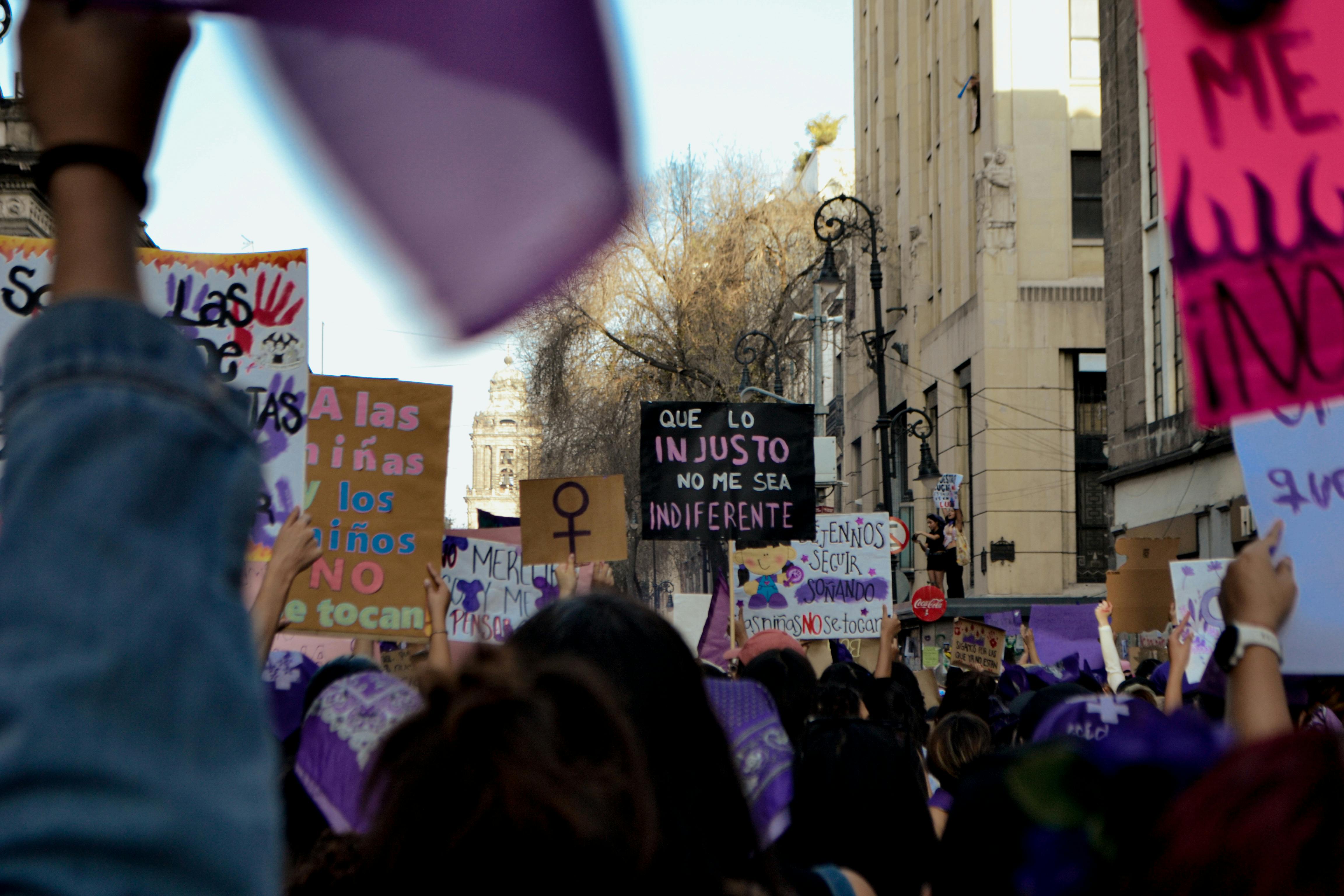 A rally advocating for women's rights with signs and banners, highlighting empowerment and equality.