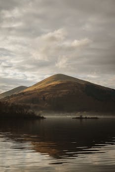 Tranquil and misty view of Loch Lomond in Scotland, capturing serene reflections.