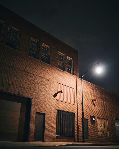Free Eerie night scene of an abandoned brick building under streetlight in Rochester, NY. Stock Photo