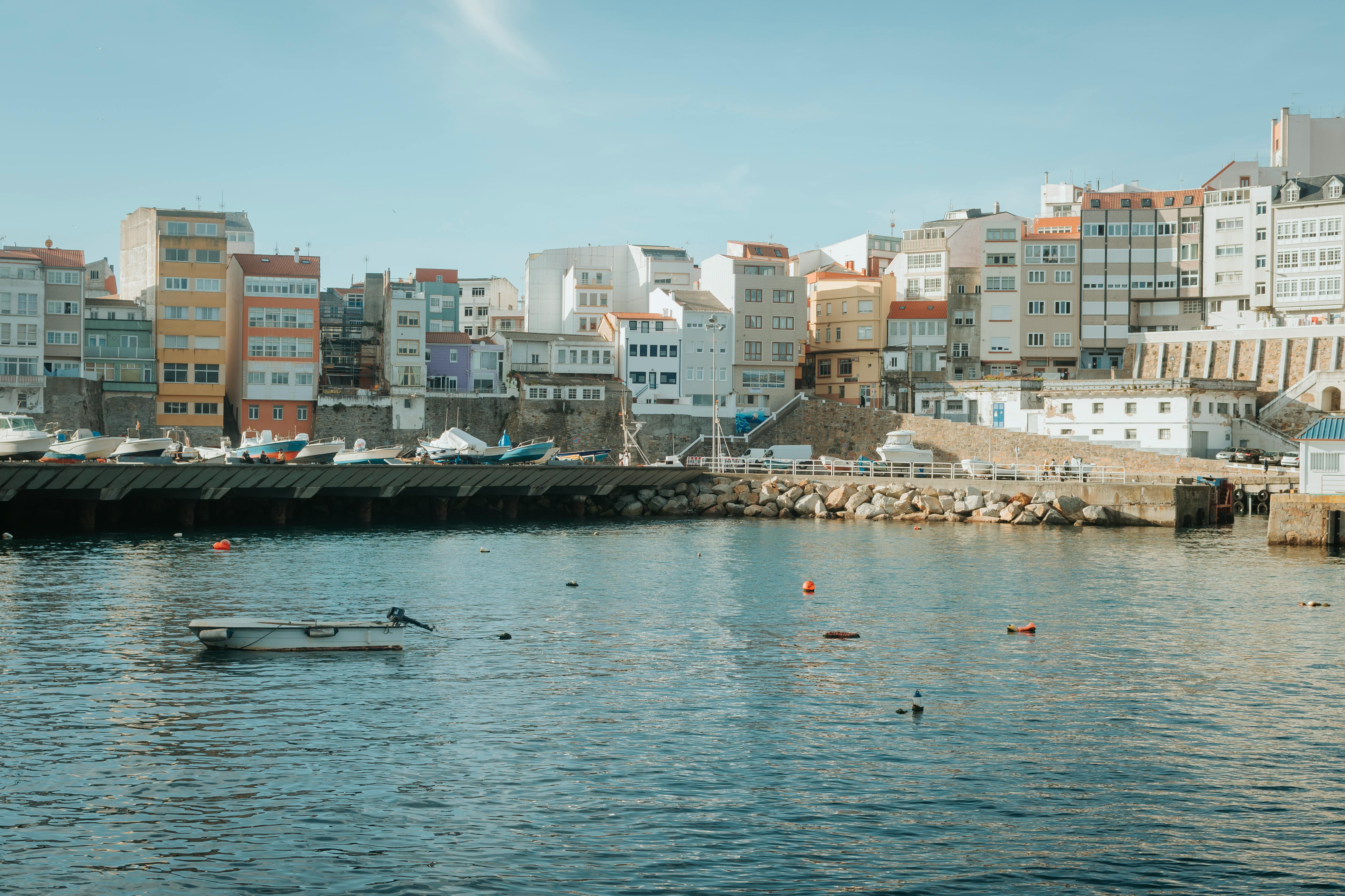 Colorful waterfront cityscape with boats docked, clear blue sky.