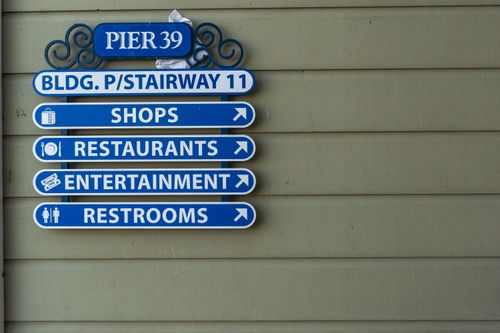 Free Blue directional sign at Pier 39 with options for shops, restaurants, entertainment, and restrooms. Stock Photo