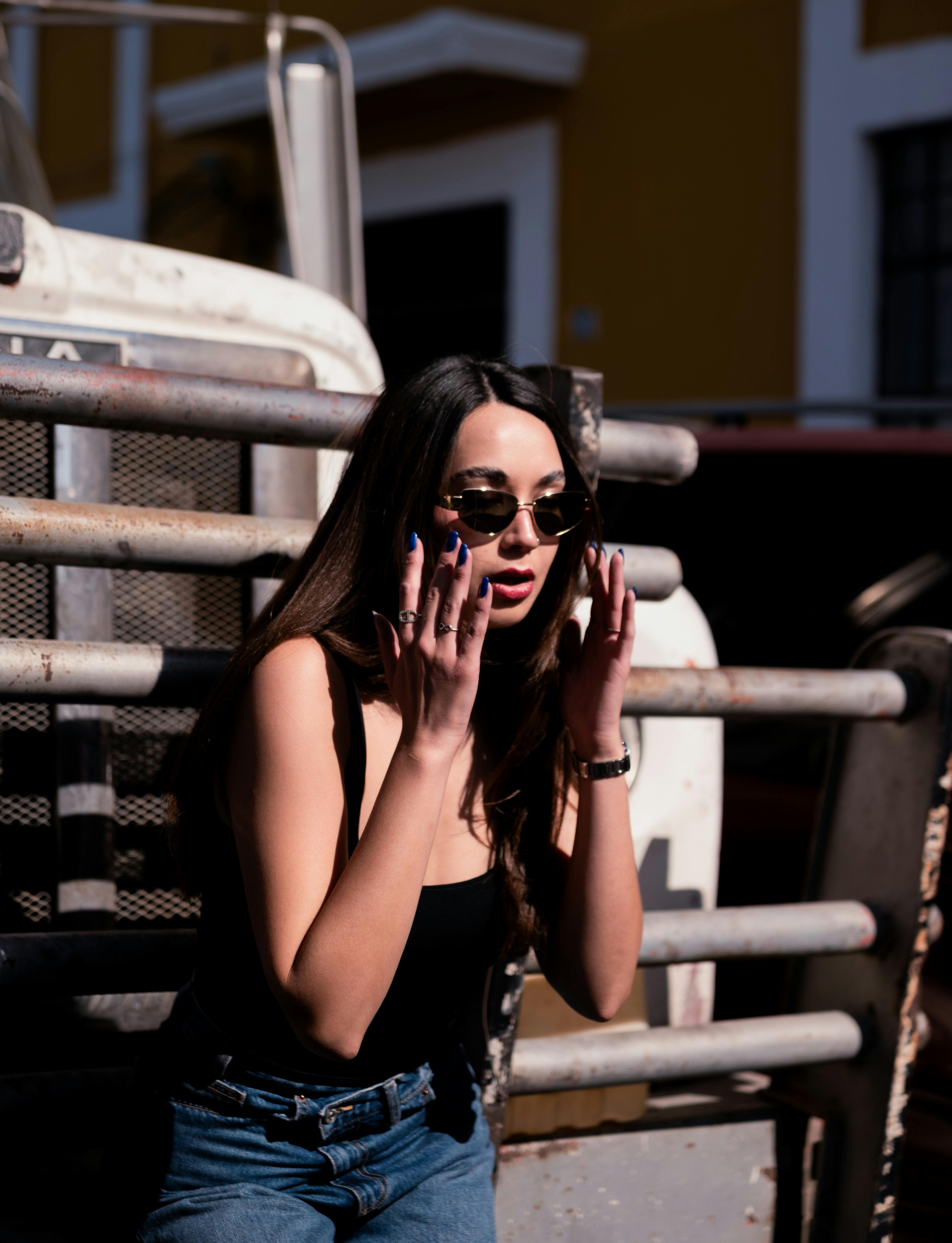 Miễn phí Người phụ nữ trẻ thời trang đeo kính râm dưới ánh nắng mặt trời và bóng râm ngoài trời. Ảnh lưu trữ