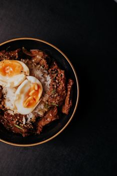 Savory beef bowl with rice and soft-boiled eggs, perfect for gourmet culinary lovers.