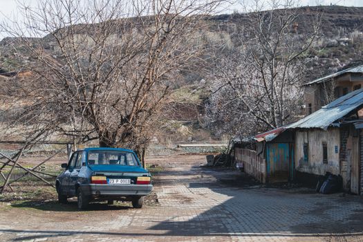 Old car parked beside rustic buildings and trees in Palu, Elazığ, Türkiye.