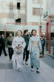 Two women in kimonos walking on a city street, showcasing traditional Japanese attire and culture.