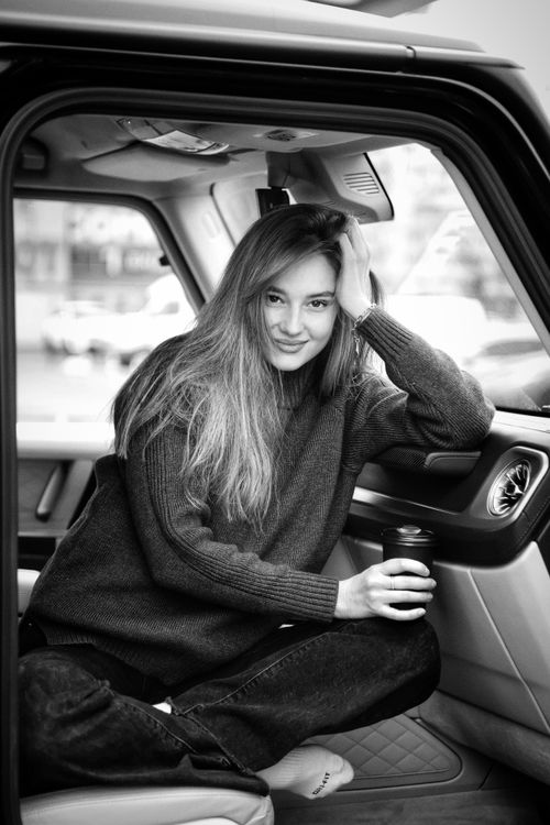 Free Young woman casually posed inside a car, expressing calm and contentment. Stock Photo