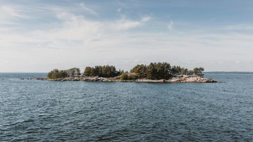 Free A tranquil view of a small forested island surrounded by calm sea under a clear sky. Stock Photo
