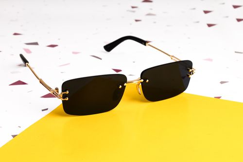 Free Elegant black sunglasses with gold accents on a vibrant yellow background. Stock Photo