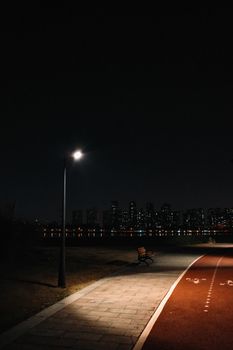 Serene cityscape at night with illuminated walking path and bench.