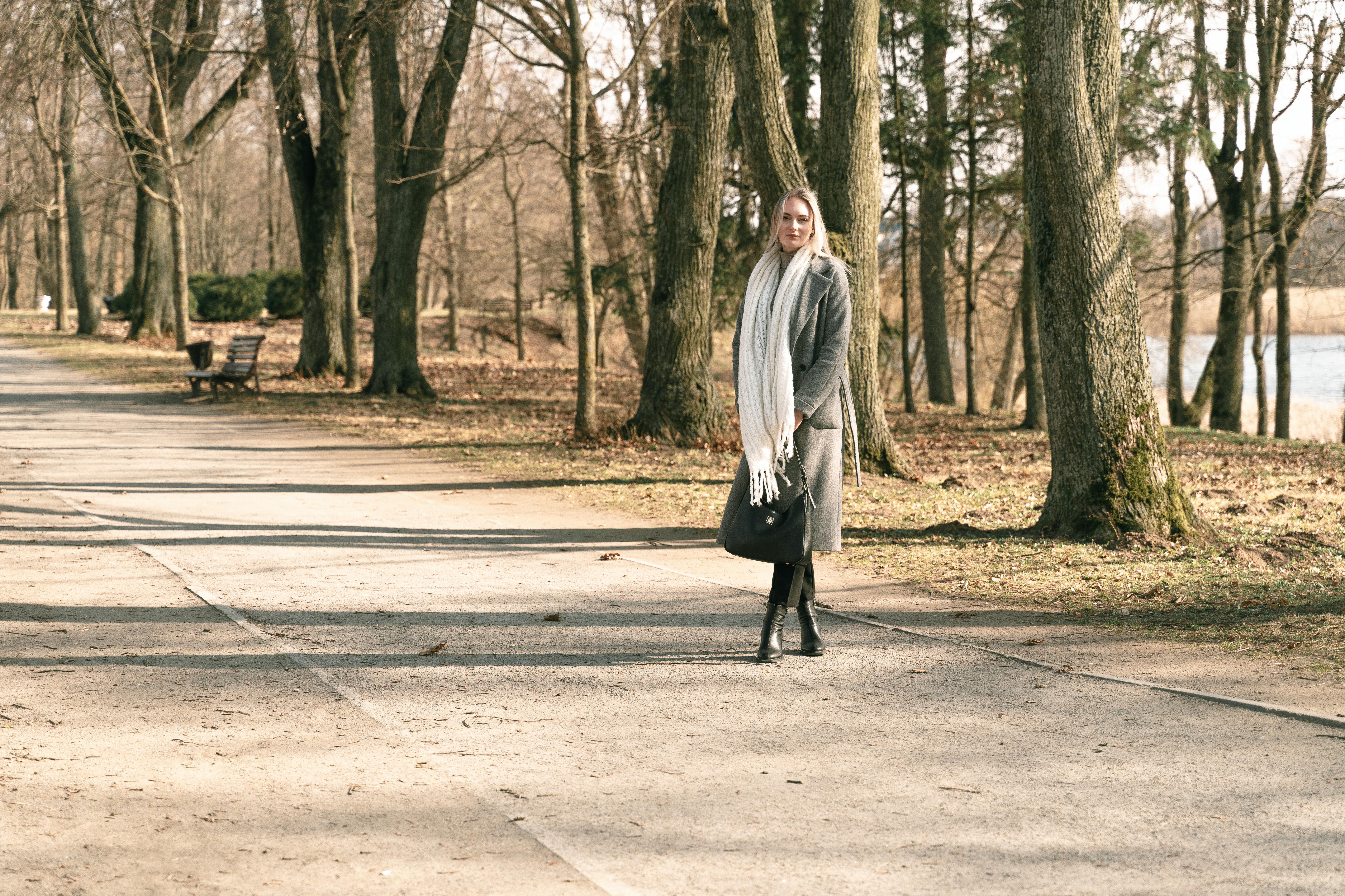 Woman walking on a sunny winter day in Niasvizh Park, Belarus, surrounded by bare trees.