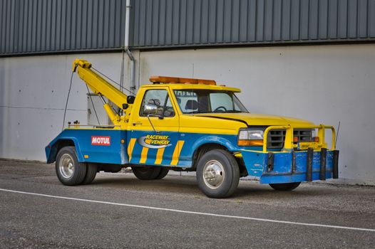 Yellow tow truck parked at Raceway Venray, showcasing automotive support in Ysselsteyn, Netherlands.
