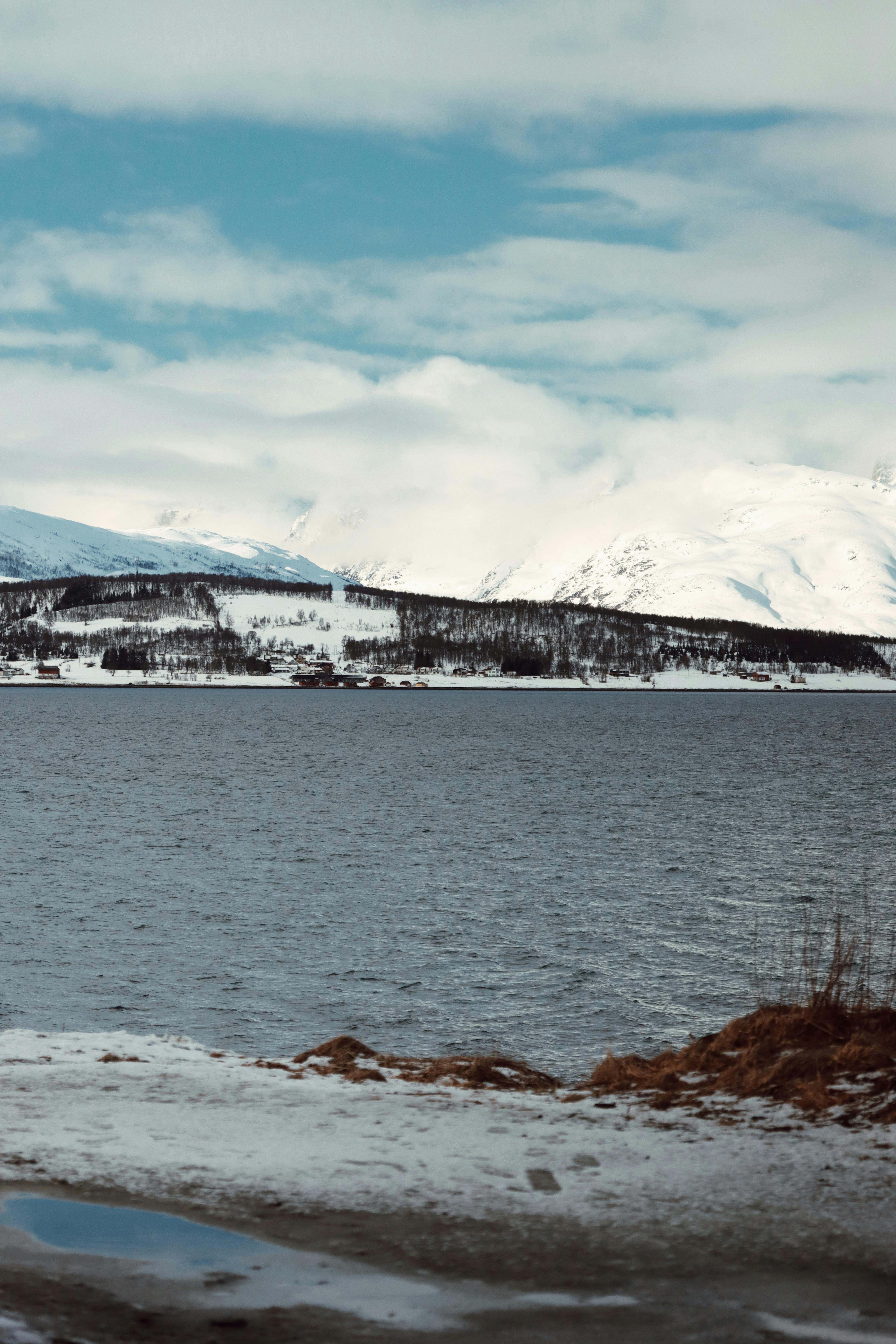 Breathtaking view of snow-capped mountains and icy waters in Tromsø, Norway, during winter.