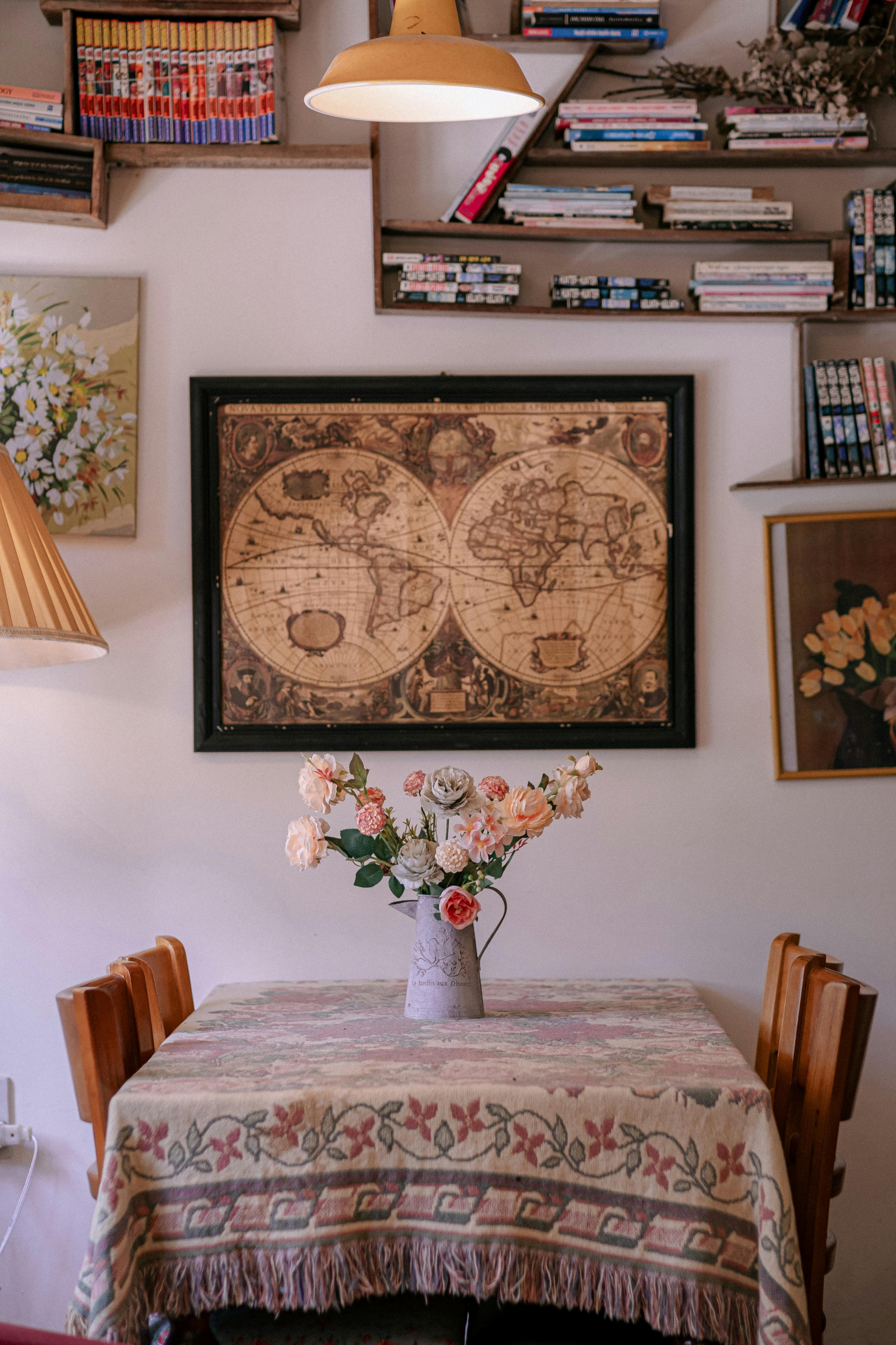 Stylish dining area with vintage map, books, and floral arrangements.