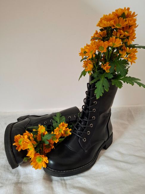 Black combat boots creatively adorned with vibrant orange flowers, exuding a unique blend of nature and fashion.
