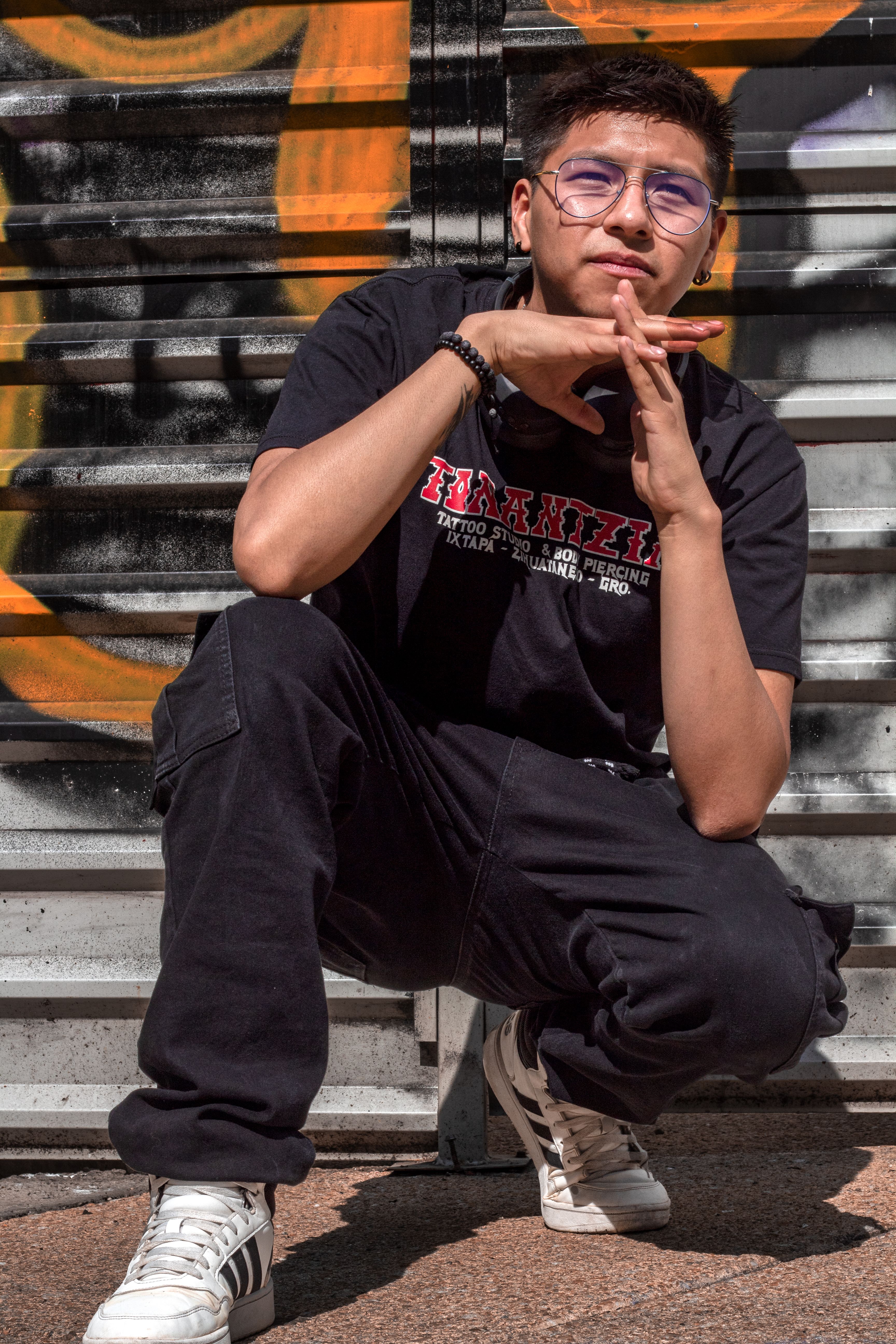 Cool street style portrait of a young man posing in front of urban graffiti art.