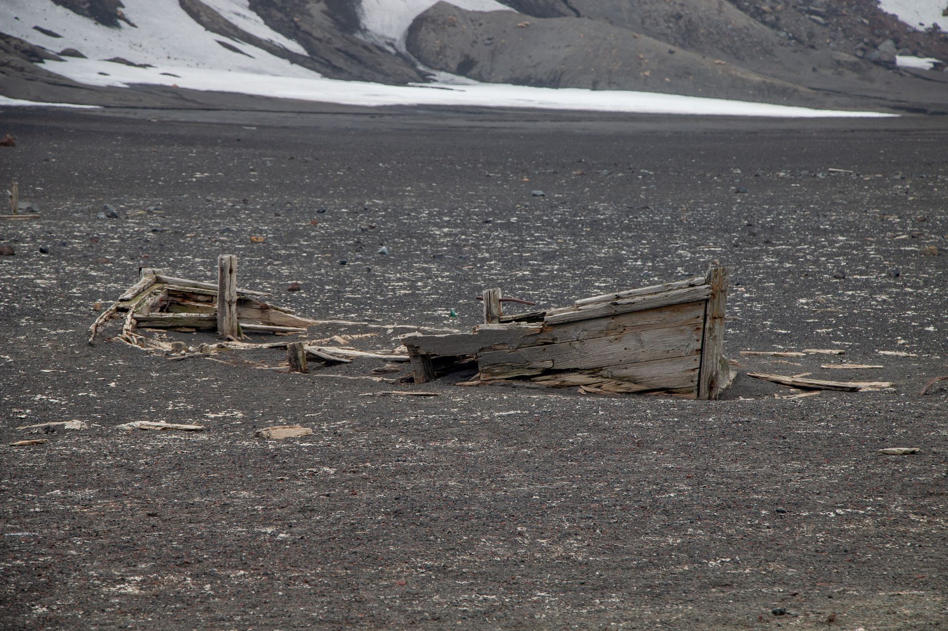 An abandoned shipwreck partially buried in a desolate Antarctic landscape, showcasing historical exploration.