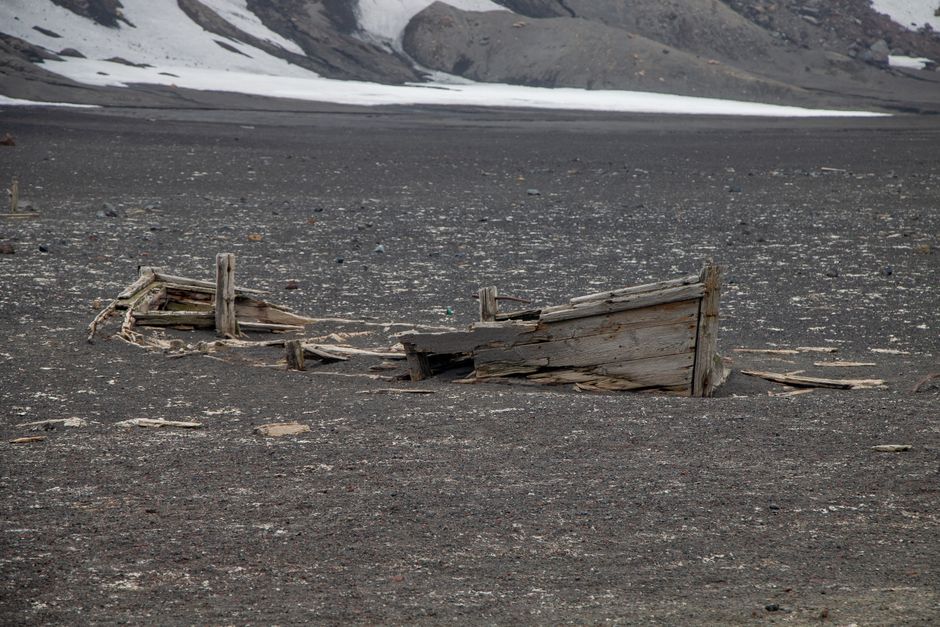 An abandoned shipwreck partially buried in a desolate Antarctic landscape, showcasing historical exploration.