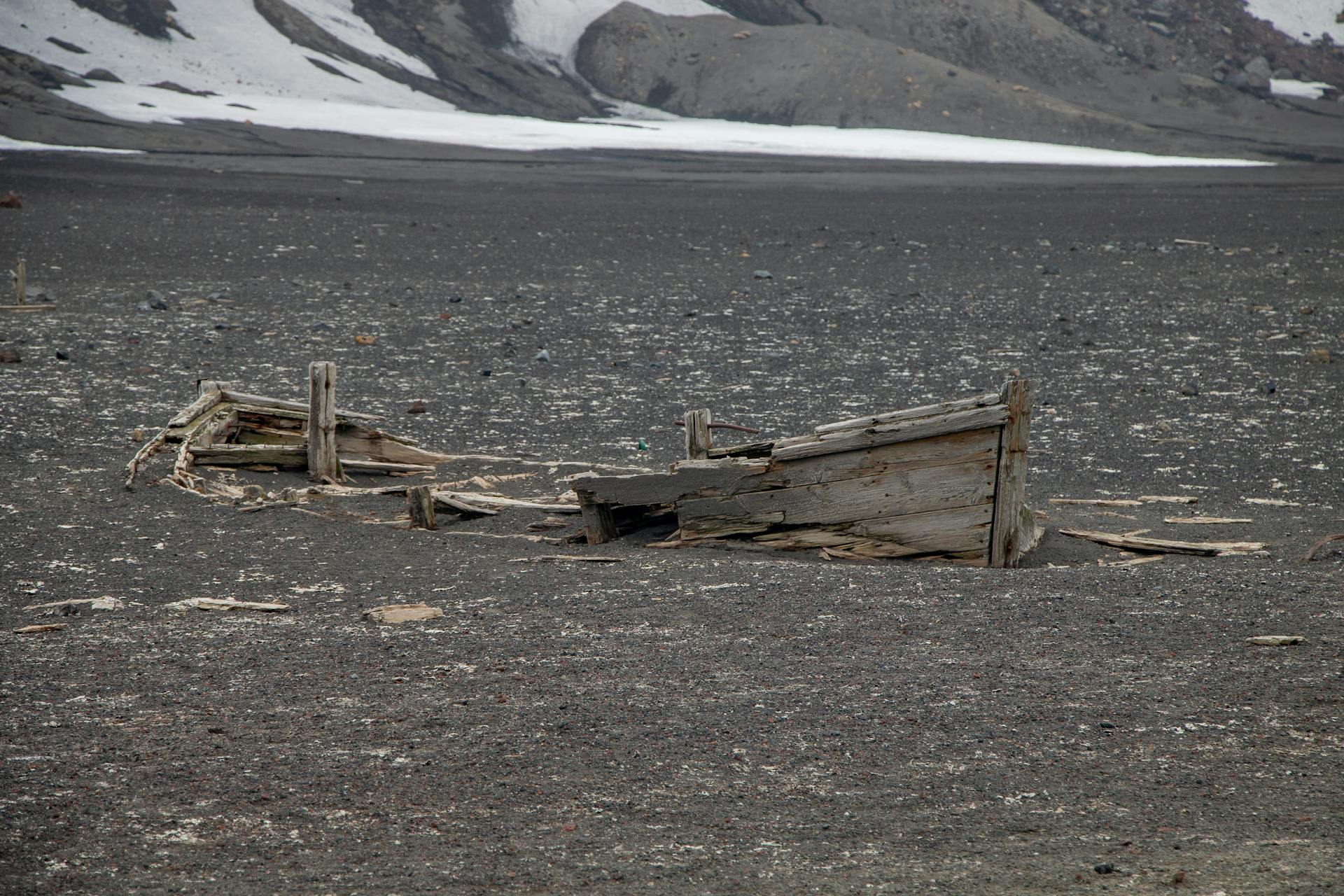 An abandoned shipwreck partially buried in a desolate Antarctic landscape, showcasing historical exploration.