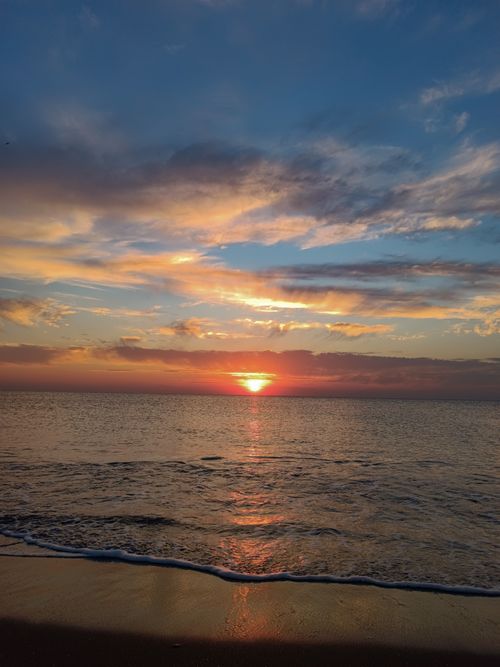 Free Beautiful ocean sunset with vibrant sky and clouds, reflecting on the water. Stock Photo