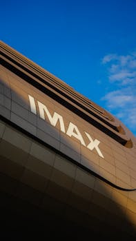 Low-angle view of an IMAX theater facade with a blue sky backdrop.