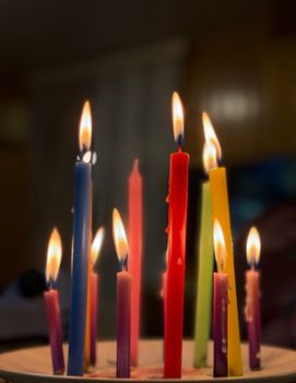 Vibrant, multicolored candles with flames, symbolizing a festive indoor occasion in Baku, Azerbaijan.