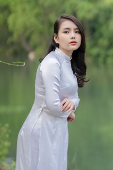 A woman in traditional dress posing outdoors by a serene lakeside.
