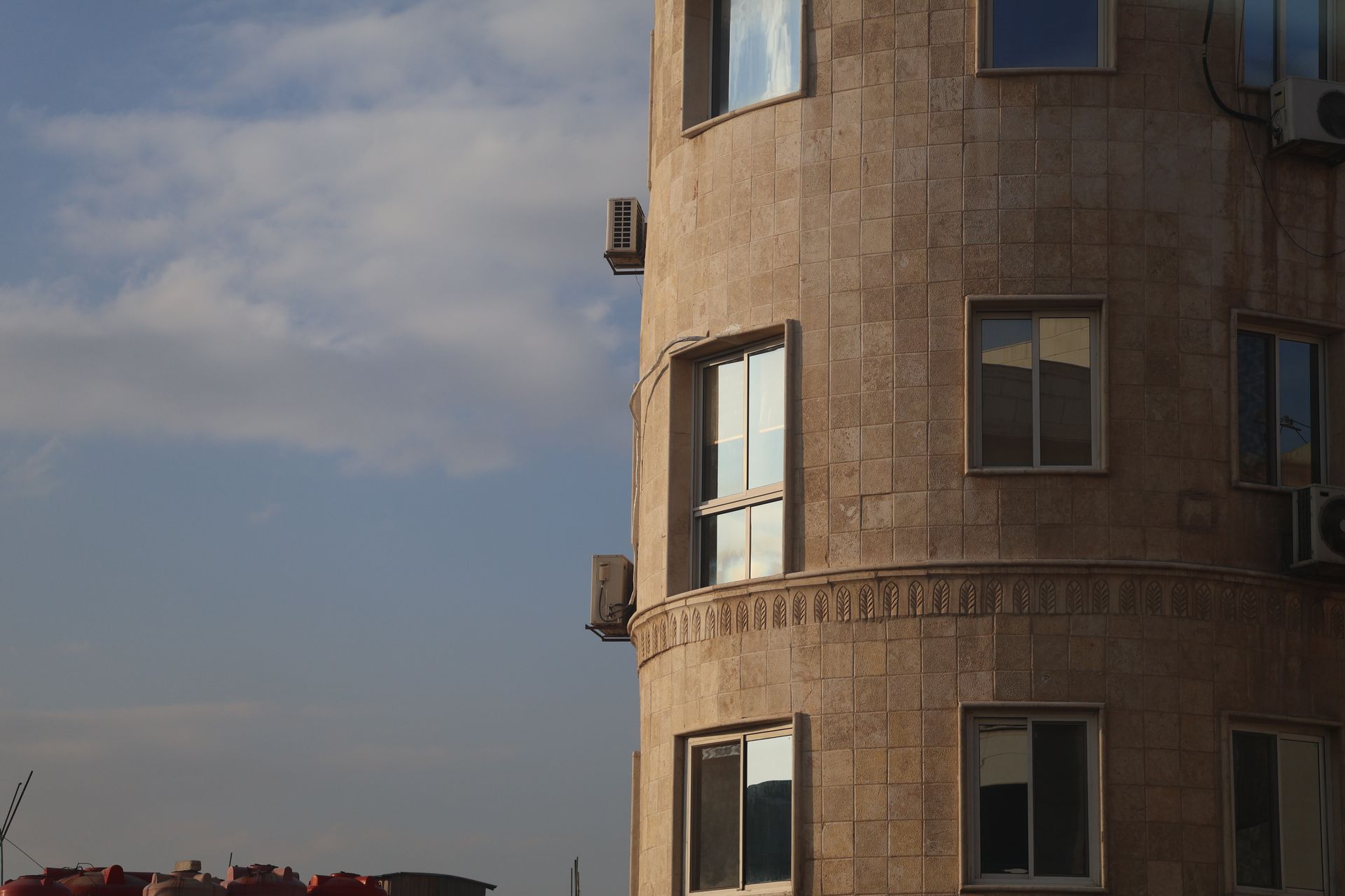 Close-up of a stone building facade in Damascus, featuring symmetrical windows and air conditioning units.