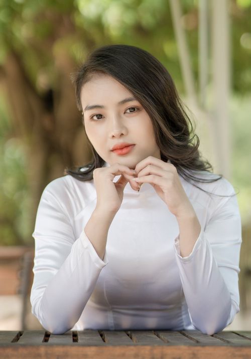 Free A serene portrait of a woman in a white top posing outdoors with a calm demeanor. Stock Photo