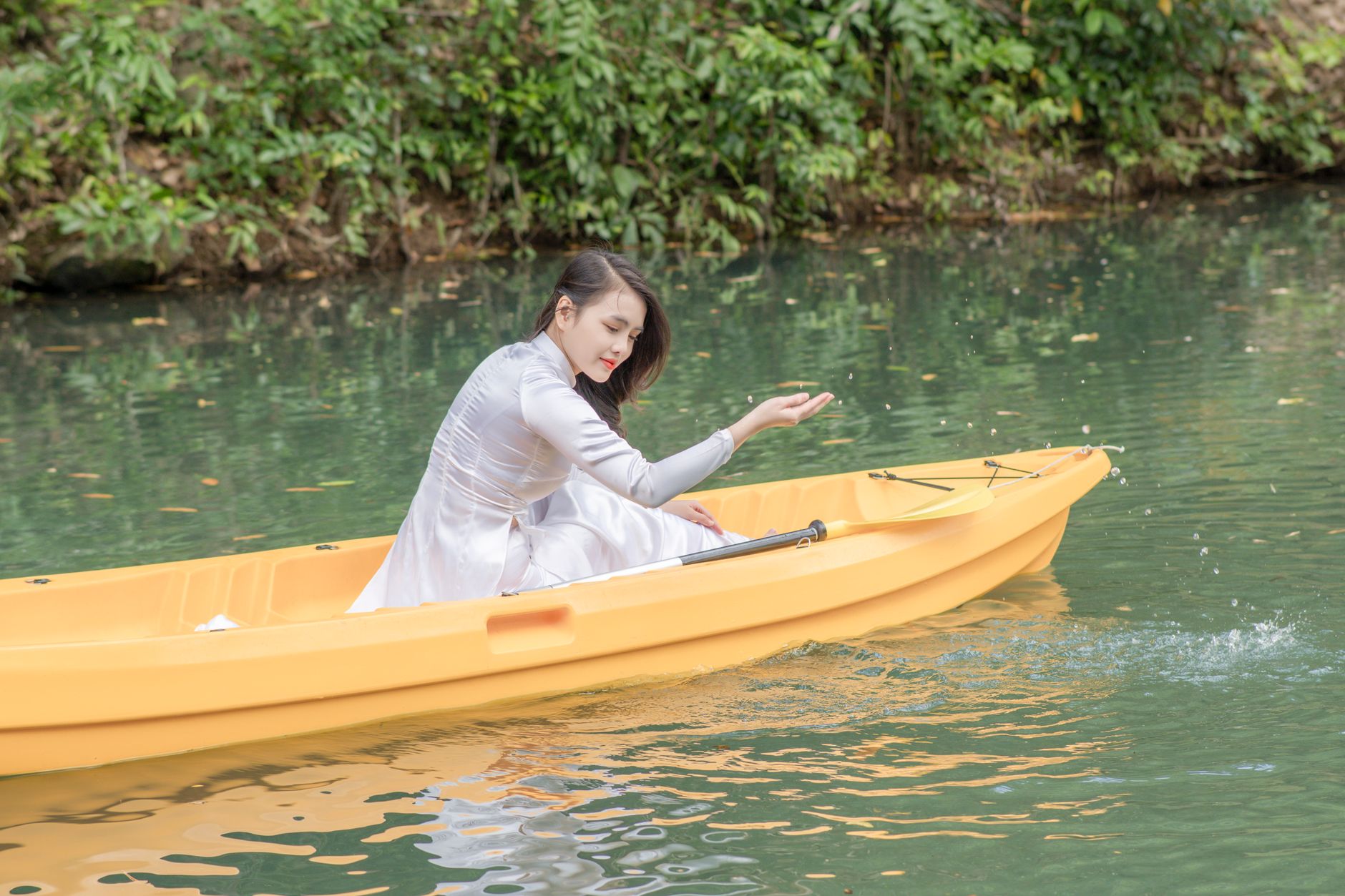 Young woman in a kayak enjoying a serene day on a lush green river.