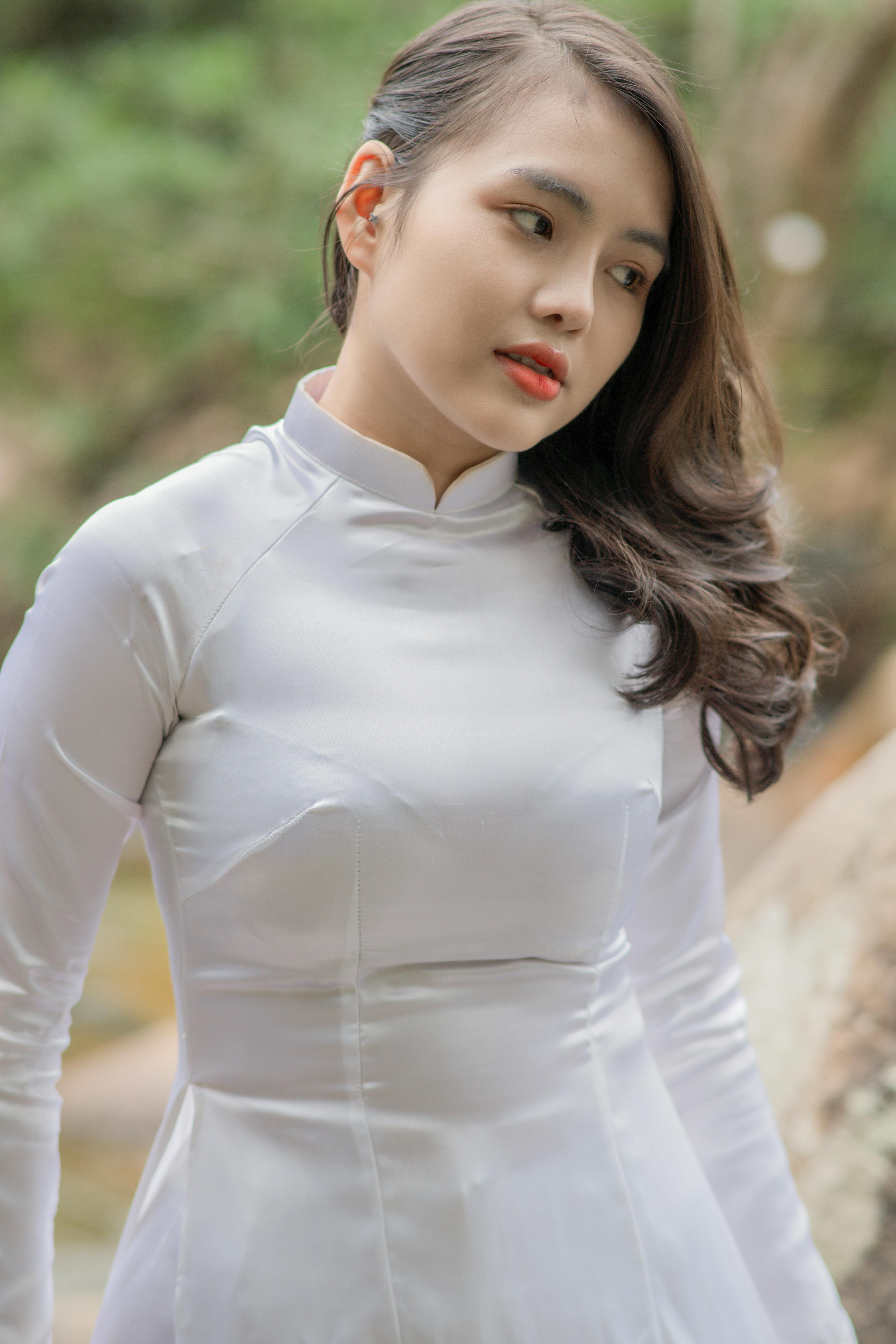 Graceful woman in white Ao Dai, serene outdoor setting.