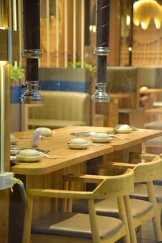 A cozy restaurant interior with a set dining table, ready for guests. Warm and inviting ambiance.