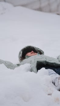 A child laying in fresh snow, dressed warmly, enjoying a peaceful winter day.