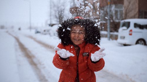 Free A joyful child in a red coat plays in the snow on a winter day, creating a vibrant scene. Stock Photo