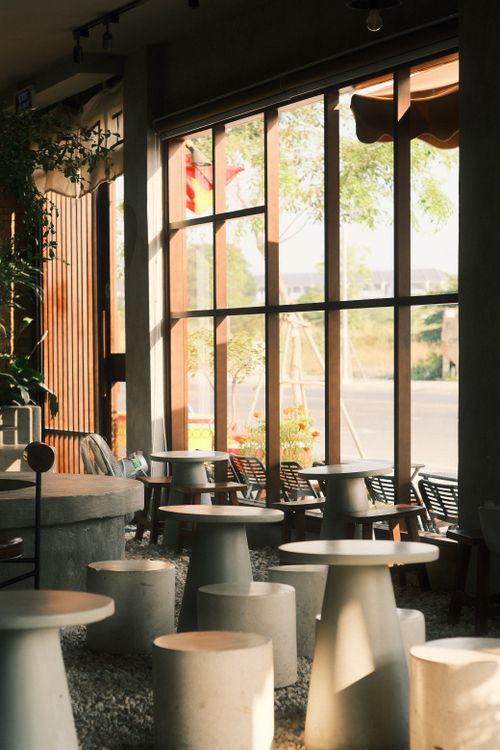 Free Stylish modern cafe interior with sunlit round tables and chairs, perfect for casual gatherings. Stock Photo