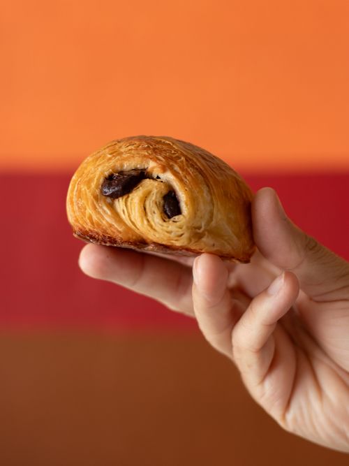 Free A hand holds a freshly baked pain au chocolat with rich chocolate filling. Stock Photo
