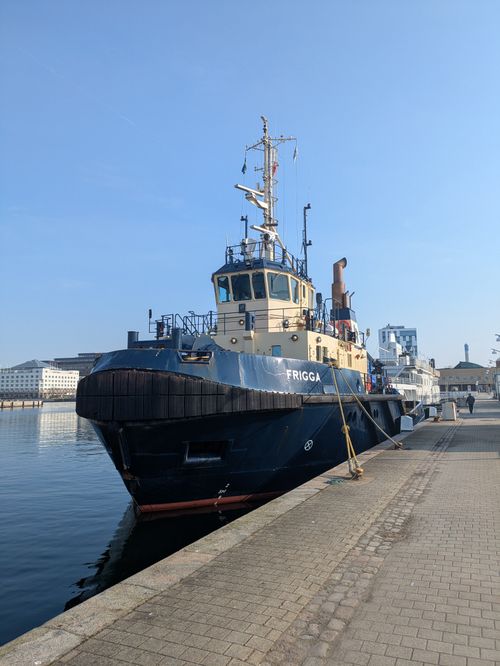 Free A tugboat named Frigga docked on a clear sunny day at a harbor. Stock Photo