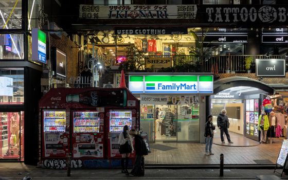 Captivating urban night scene of Shinsaibashi, Osaka featuring vending machines, shops, and pedestrians.