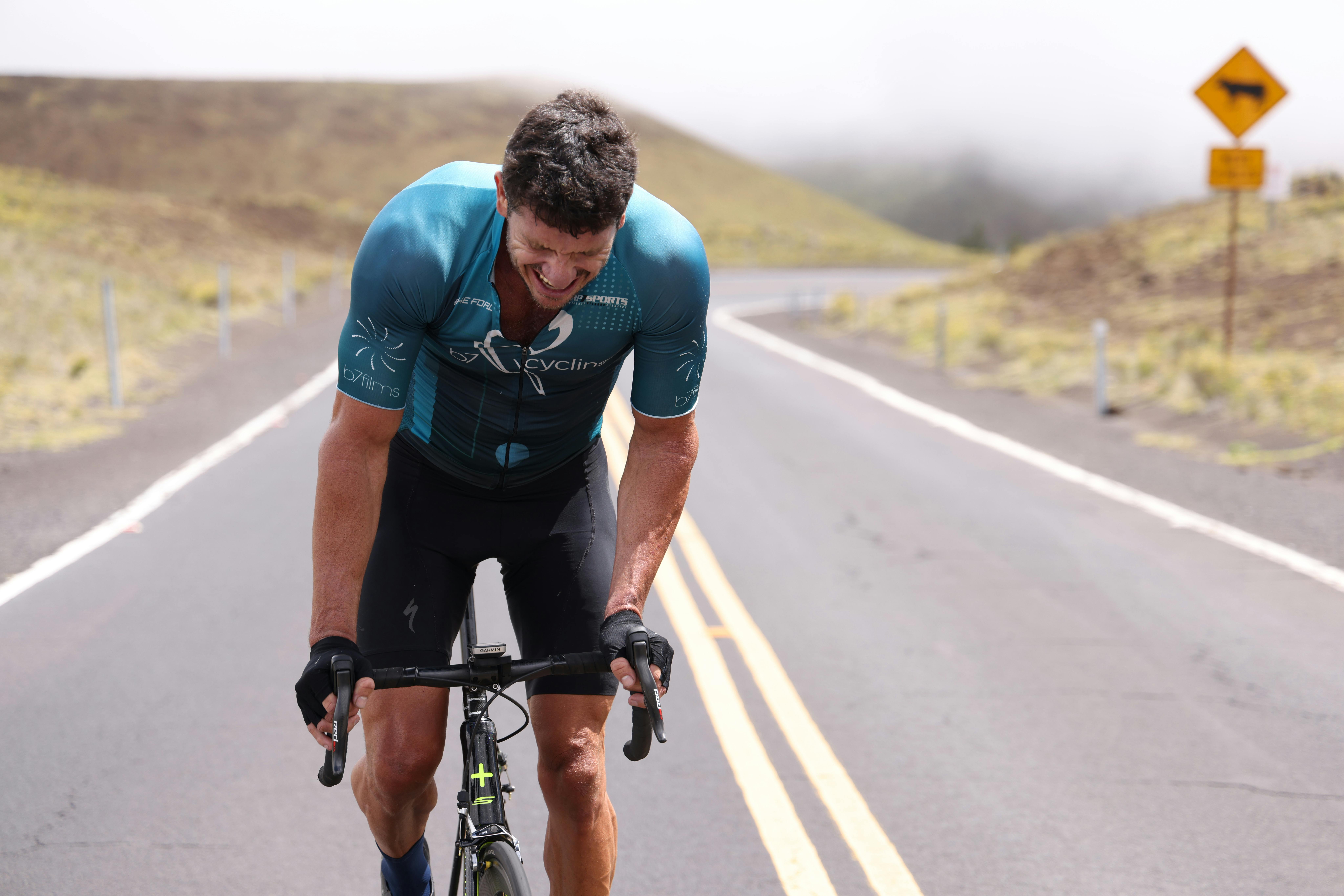 Determined cyclist pushing hard uphill on a remote mountain road in a race.