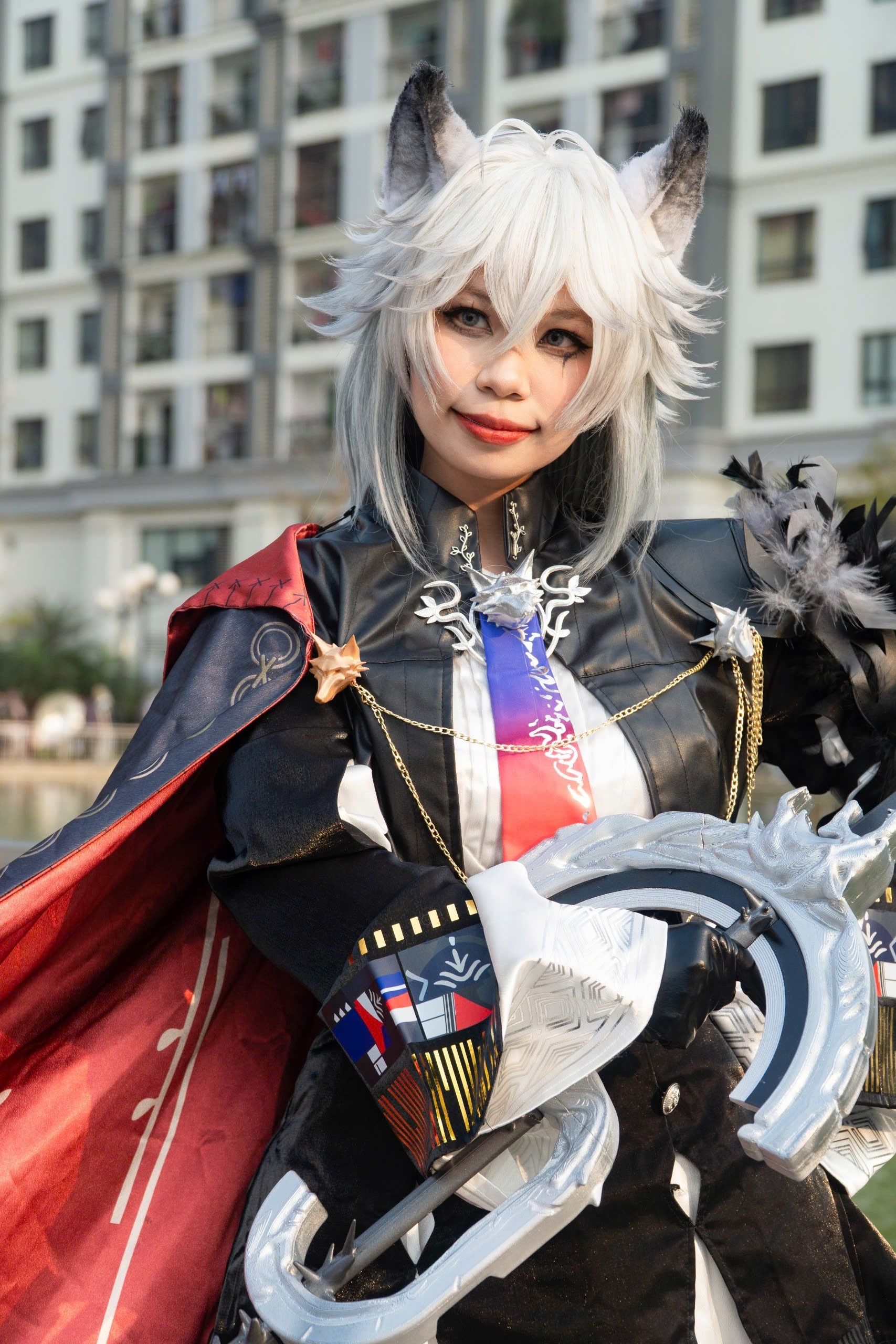 A cosplayer in a detailed fantasy costume poses outdoors with a confident expression.