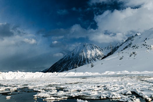 A breathtaking snow-covered mountain landscape under a cloudy blue sky, captured in winter.